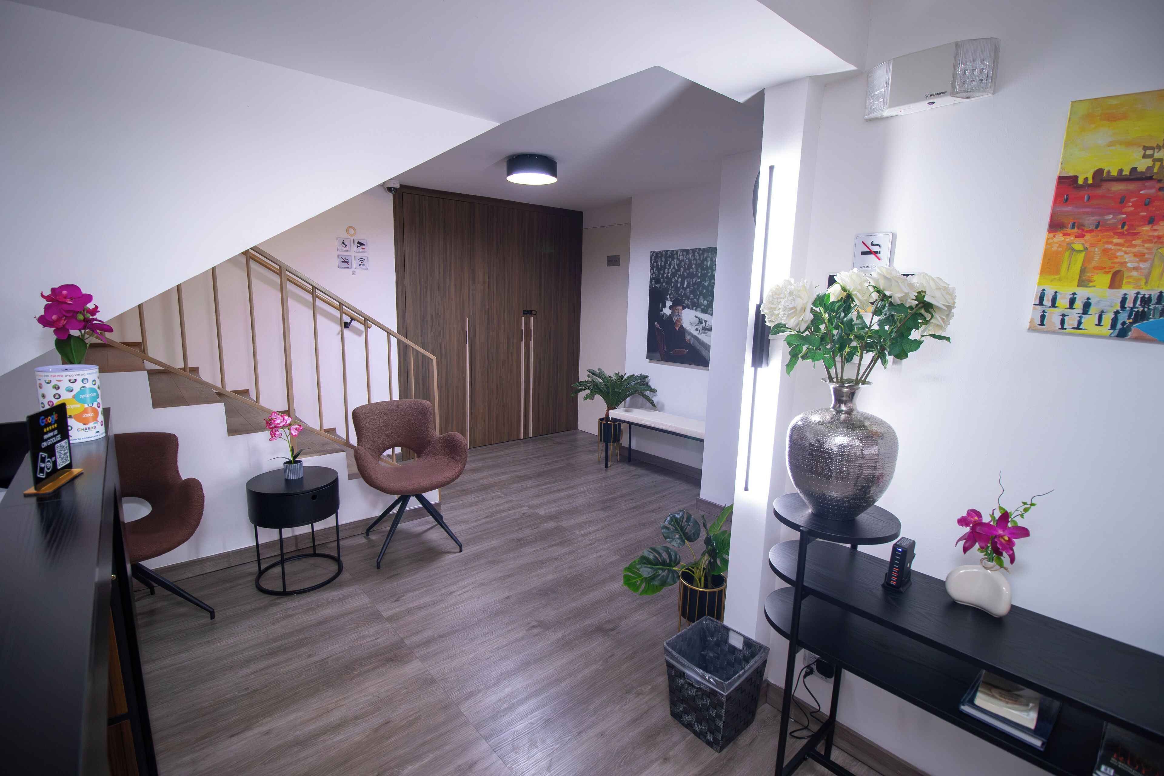 Een moderne woonkamer met een trap, houten vloeren en een mix van meubels, waaronder een bank, stoelen en een console met decoratieve items.
