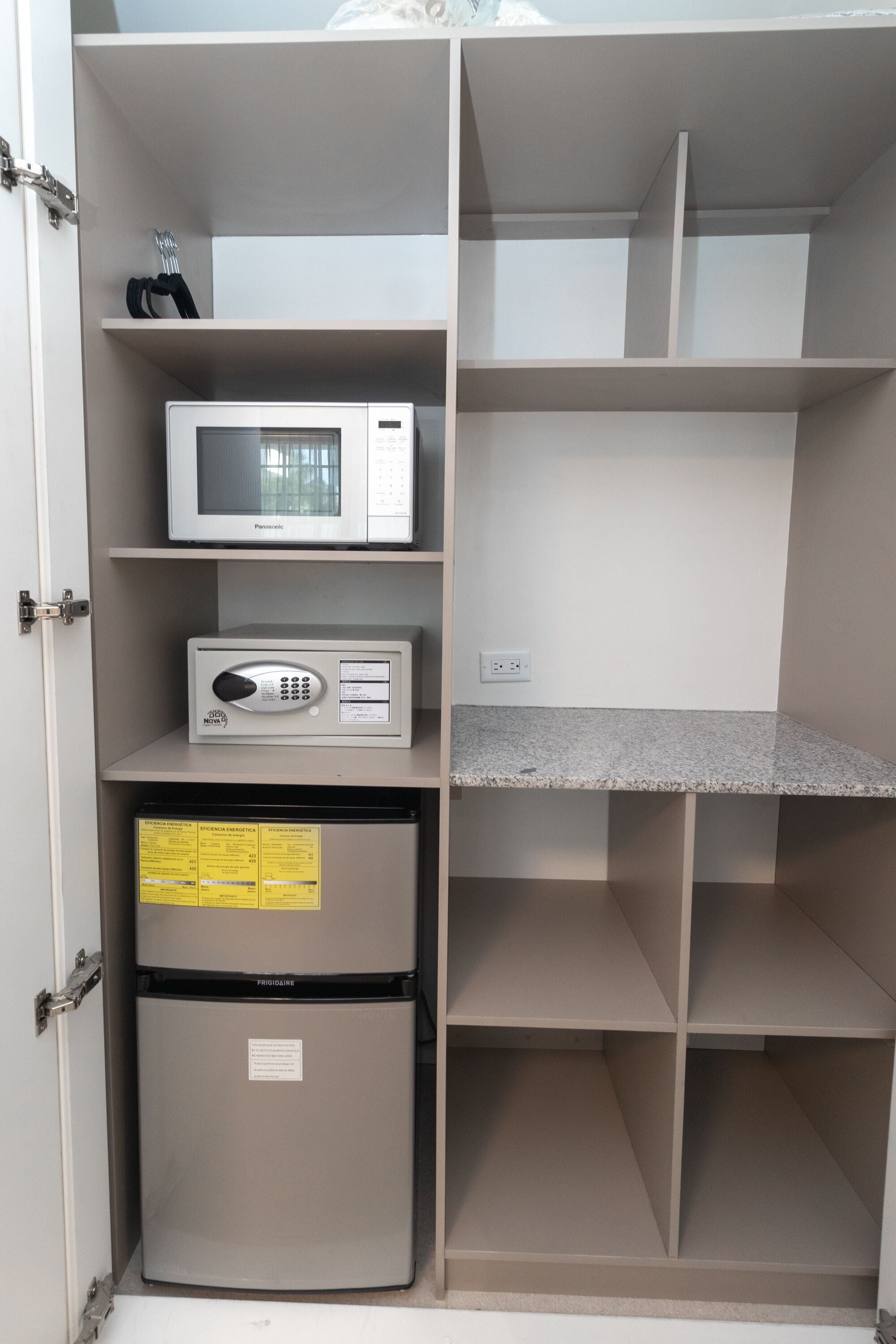 Una cocina con microondas, refrigerador y encimera de granito.
