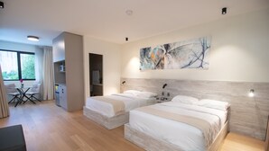 Een moderne hotelkamer met twee bedden, een eethoek en een groot abstract schilderij aan de muur.