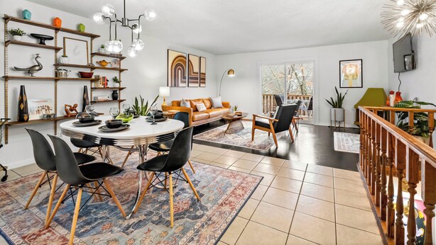 Una sala de estar moderna con una mesa de comedor redonda, sillas negras, un sofá y una escalera.