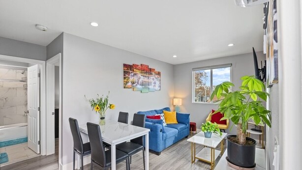 Un salon moderne avec un canapé bleu, une table à manger et des chaises, une plante en pot et un tableau accroché au mur.