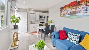 Un salon moderne avec un canapé bleu, une table basse et un coin repas comprenant une table et des chaises blanches.