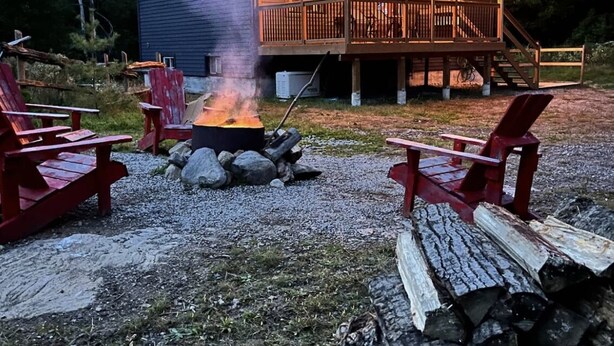 A cabin with a deck, outdoor seating, and a fire pit. - Cozy Cabin In The Woods  (Sprucedale)
