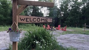 A wooden sign with the word "WELCOME" and a flower cart with potted plants. - Cozy Cabin In The Woods  (Sprucedale)