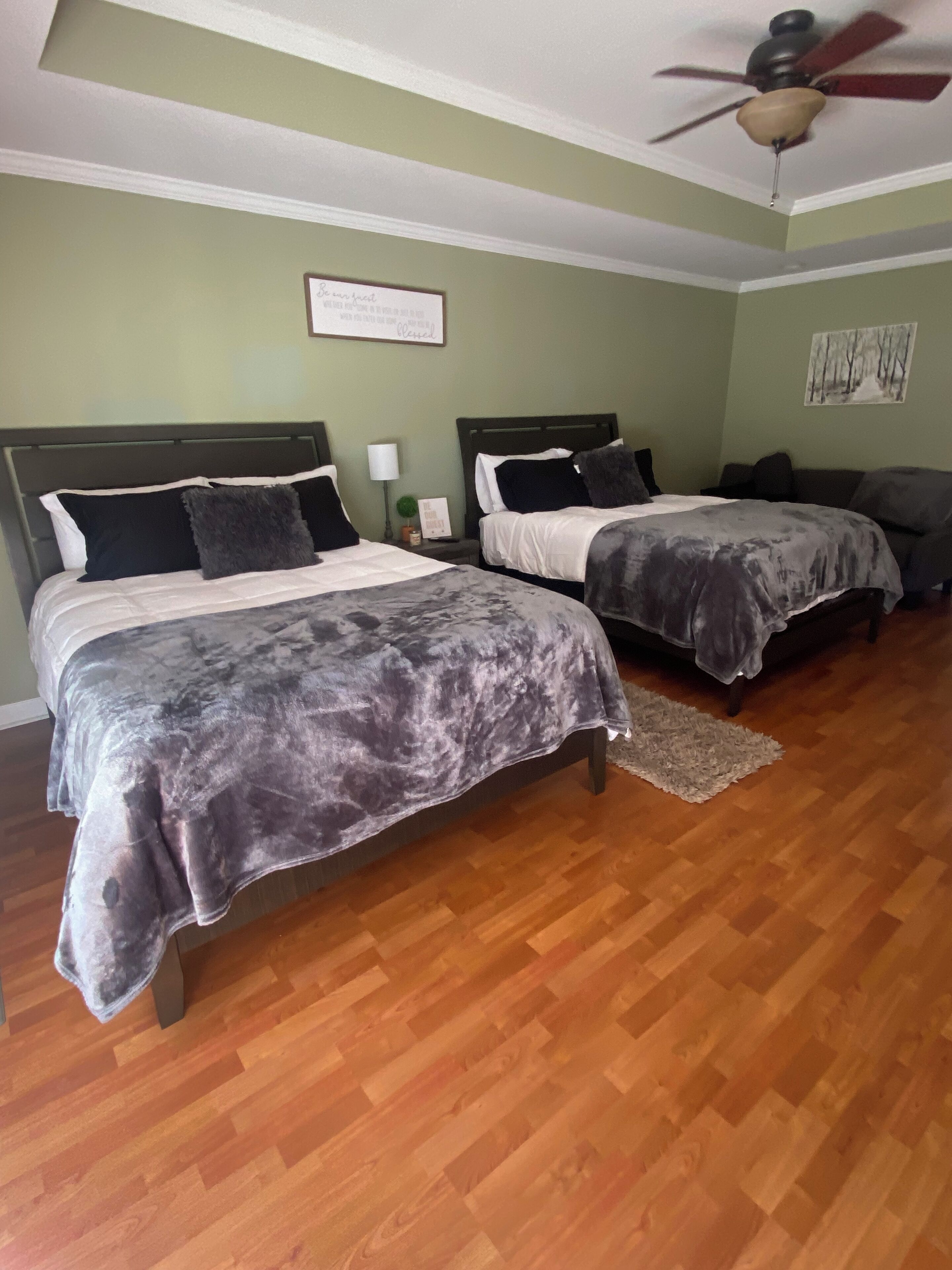 A bedroom with two beds, a ceiling fan, and a wooden floor.