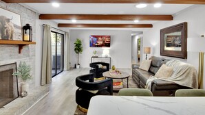 A modern living room with a fireplace, a sofa, a coffee table, and a TV mounted on the wall. - Large/Modern Home, Walk to Paris Mtn. State Park (Greenville)