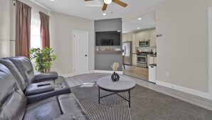 Un salon moderne avec un canapé en cuir, une table basse ronde et un ventilateur de plafond.