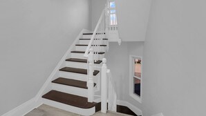 Un escalier blanc avec des marches sombres menant à un palier.