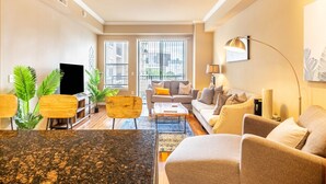 Una sala de estar moderna con un televisor de pantalla plana, un conjunto de sofás, una mesa de centro y un comedor con sillas.