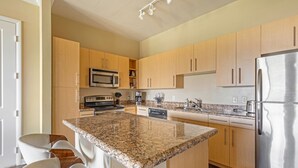 Una cocina moderna con encimeras de granito, electrodomésticos de acero inoxidable y armarios de madera.