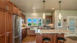 Una cocina moderna con armarios de madera, electrodomésticos de acero inoxidable y una isla grande con taburetes.