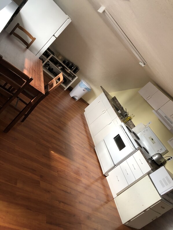 A kitchen with wooden flooring, white cabinets, and a dining area with a wooden table and chairs. - Cozy 2 Bedroom Apartment
Hardisty AB
Fully Equipped & =Furnished (Hardisty)