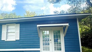 A single-story house with a dark blue exterior, white trim, and a front door with glass panels.