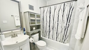 A bathroom with a toilet, sink, mirror, and shower curtain.