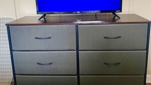 A flat-screen TV on a wooden cabinet with drawers.