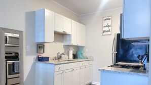 A modern kitchen with white cabinets, a built-in oven, a coffee maker, and a sign on the wall.