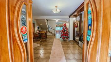 A hallway with a wooden floor, a Christmas tree, and a staircase leading to another room.