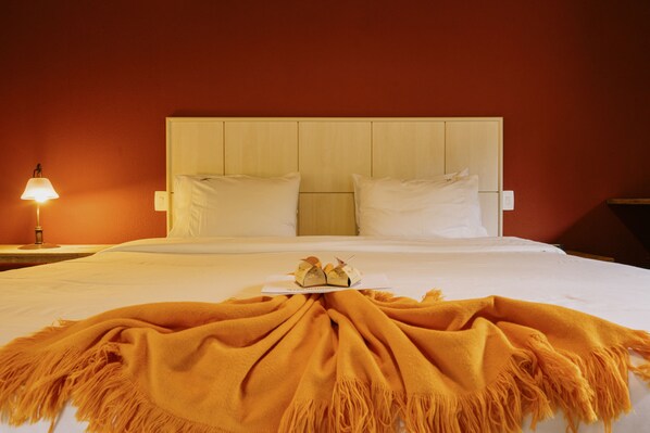 Una habitación de hotel con una cama, una mesita de noche con una lámpara y una colcha en la cama.