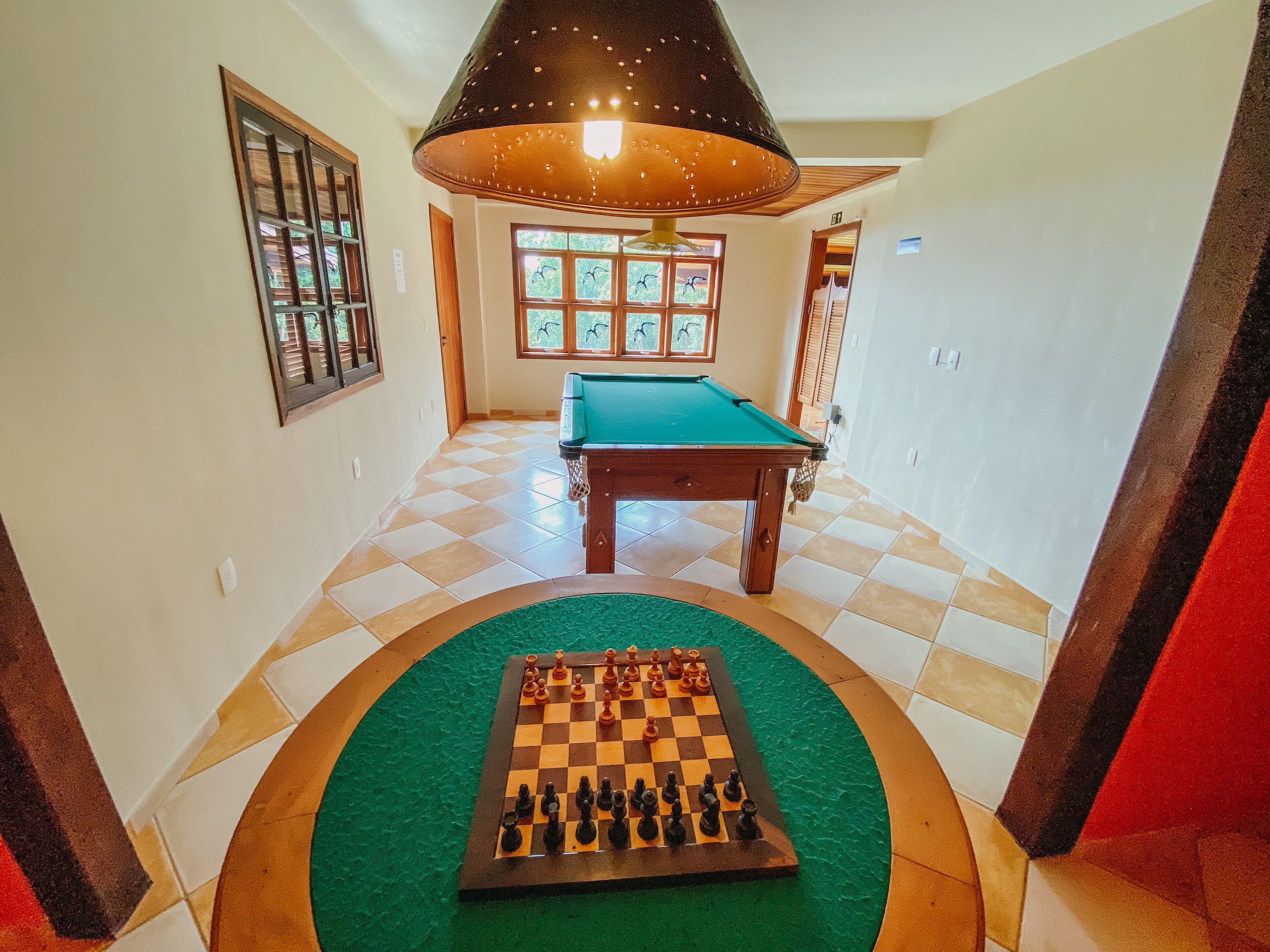 A hallway with a pool table, a green carpet, and a chessboard.