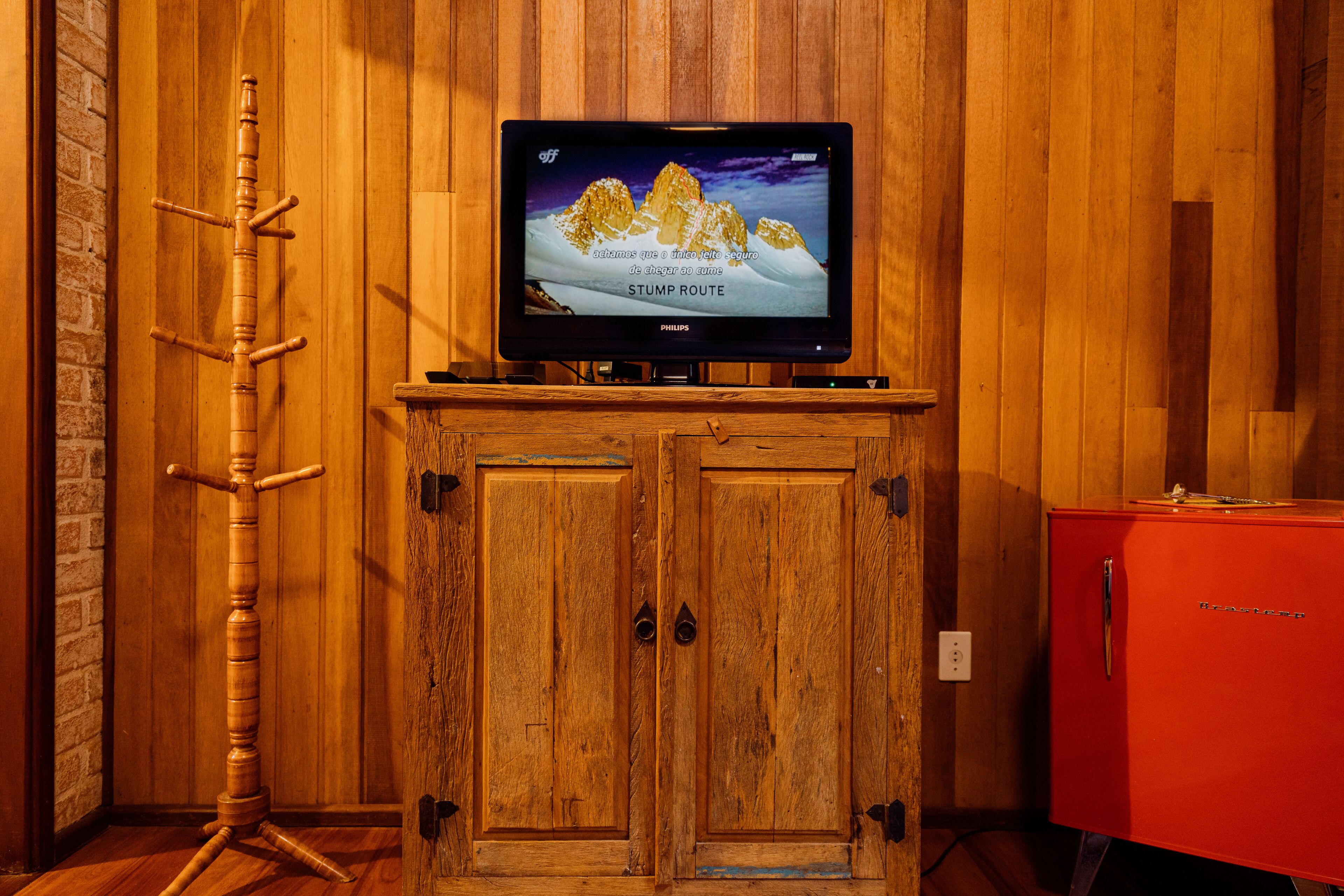 A wooden cabinet with a television on top displaying a mountain scene.