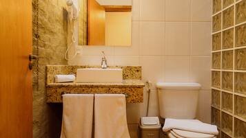 A bathroom with a granite countertop, a white sink, a toilet, and a mirror above the sink. There are two towels hanging on the wall.