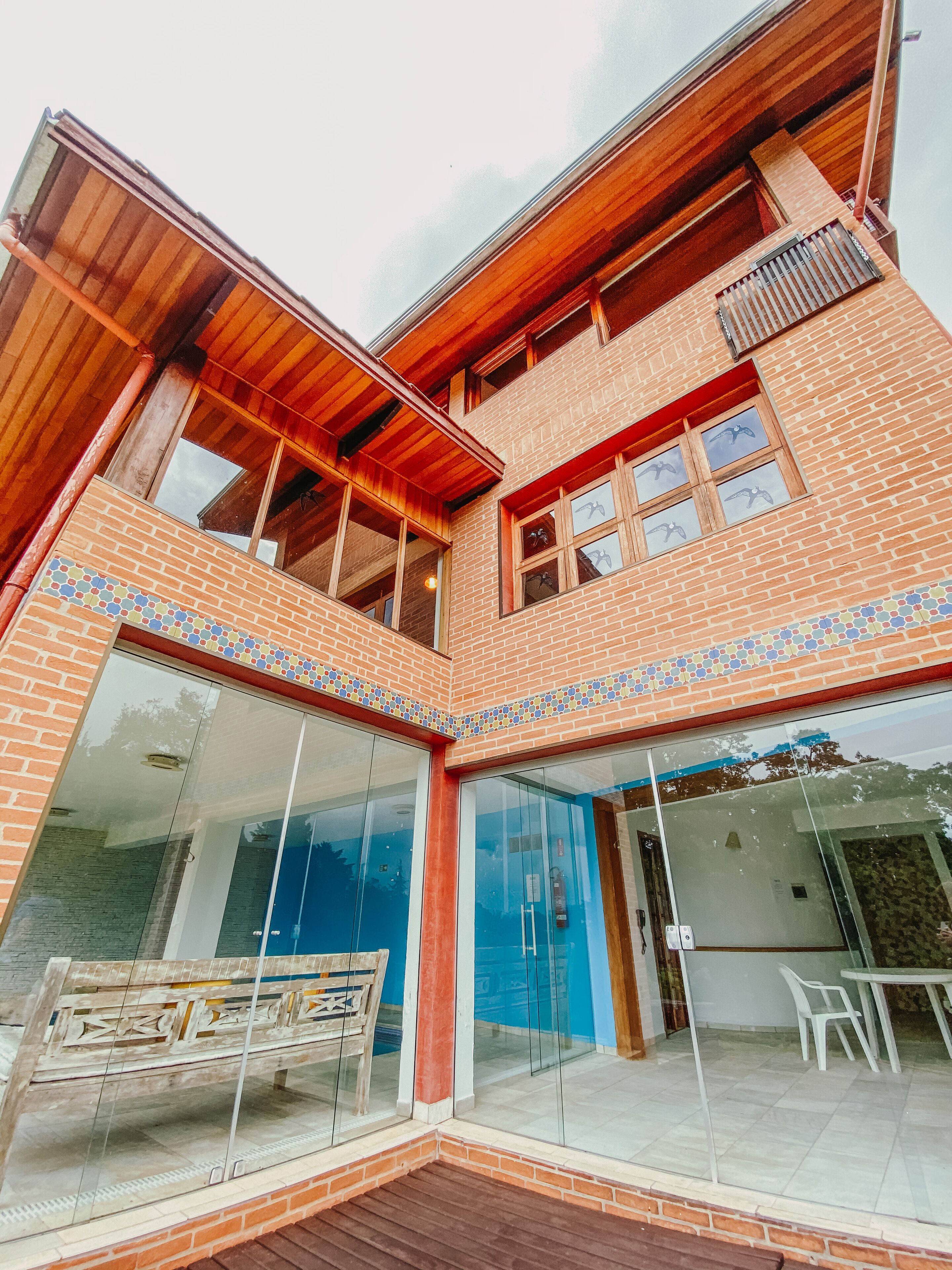 A modern house with a glass facade, wooden balconies, and a tiled roof.