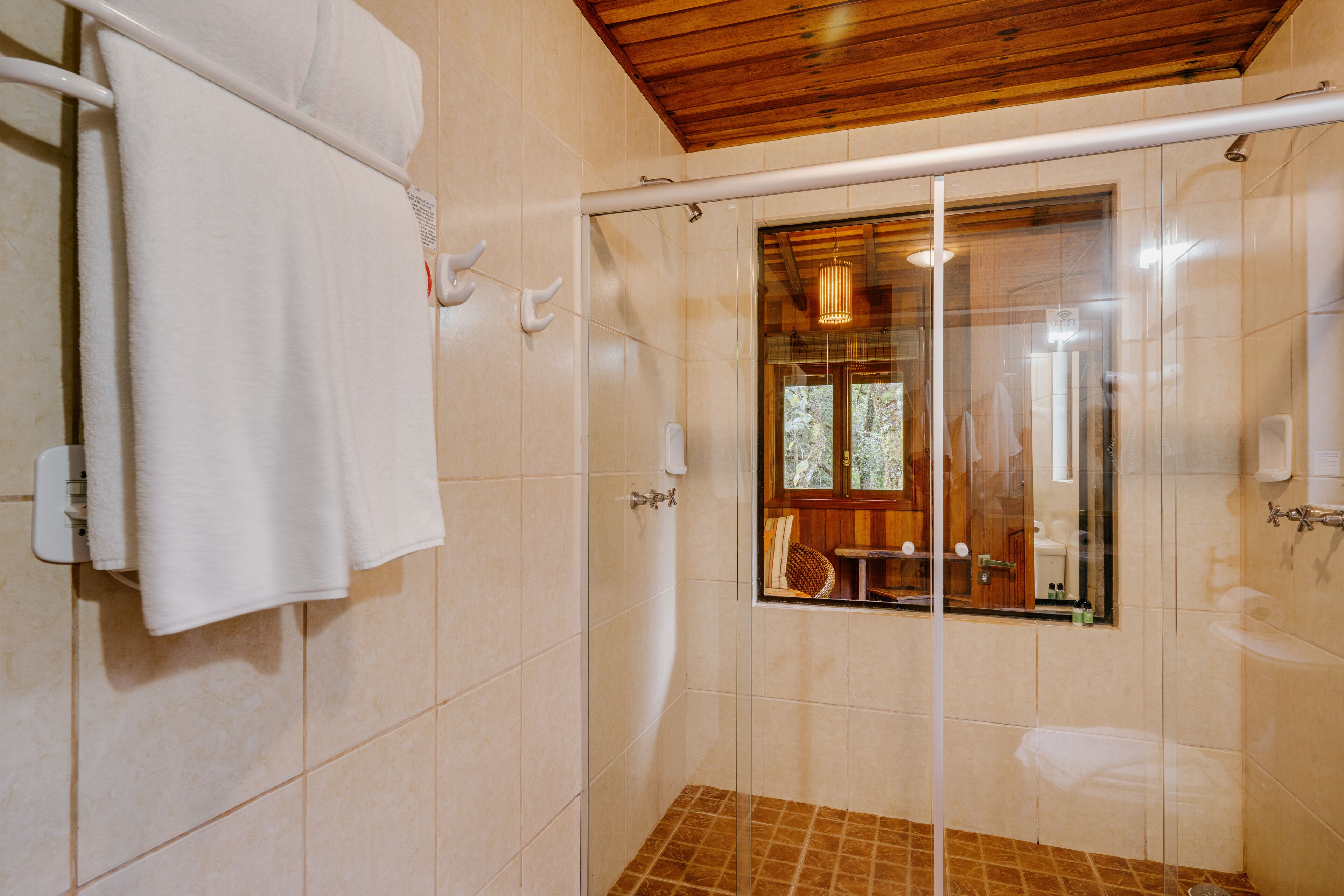 A shower with a glass door, a towel rack, and a wooden ceiling.