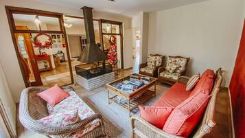 A living room with wicker furniture, a fireplace, and a Christmas tree.