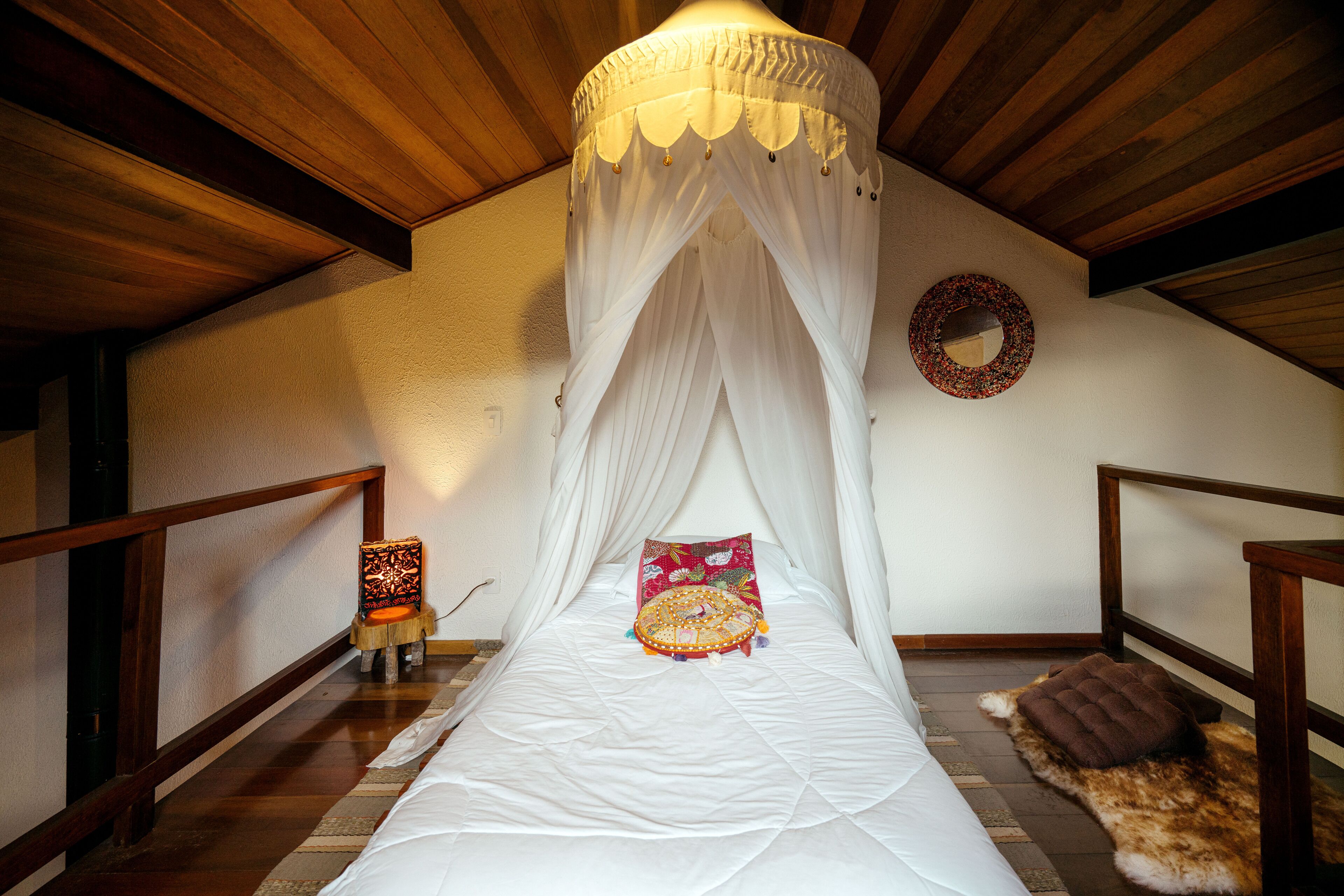 Un dormitorio con cama a dosel, una mesita de noche con lámpara y una alfombra en el suelo.
