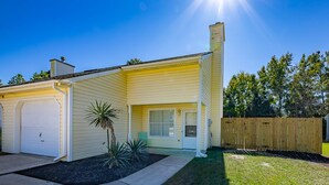 Une maison de plain-pied avec un garage, un porche à l’avant et un petit jardin agrémenté d’un palmier.