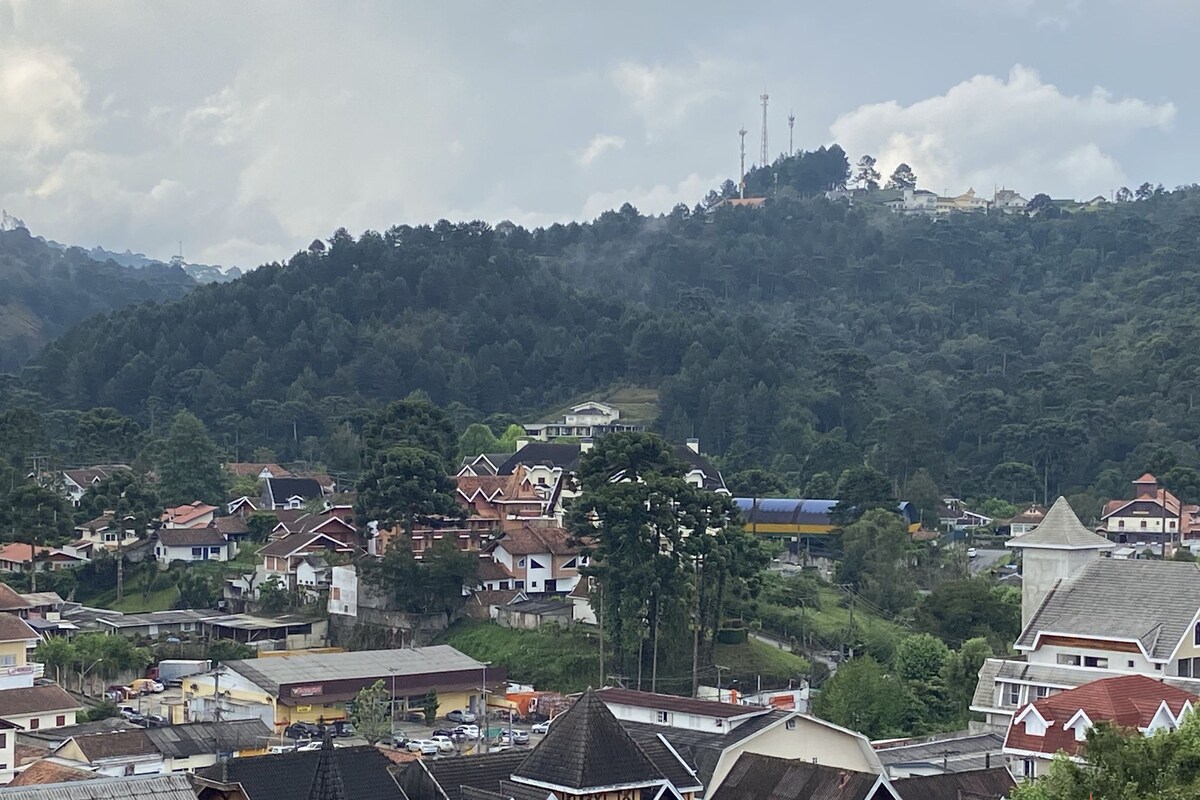 A town with traditional houses, a prominent church, and a hill with dense greenery in the background.