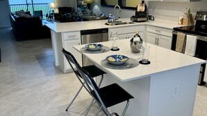 A modern kitchen with a large island, white cabinetry, and a view to the outside.