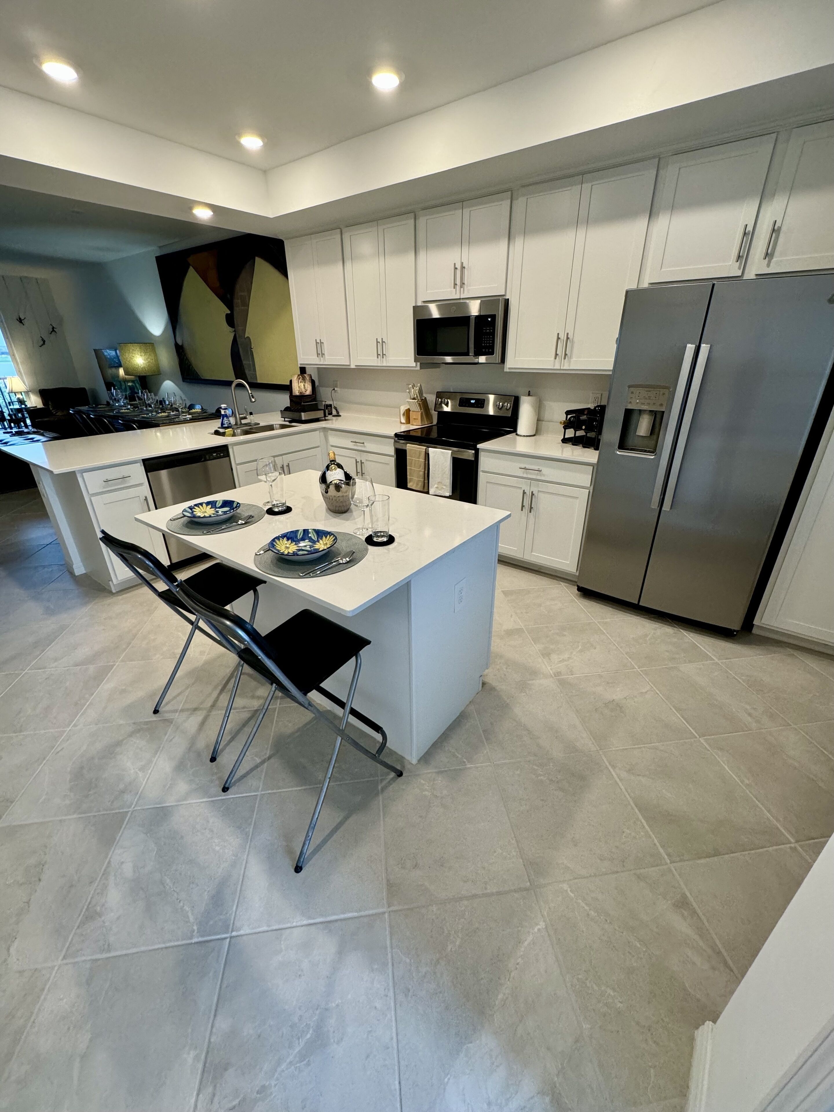 A modern kitchen with white cabinetry, stainless steel appliances, and a central island with seating.