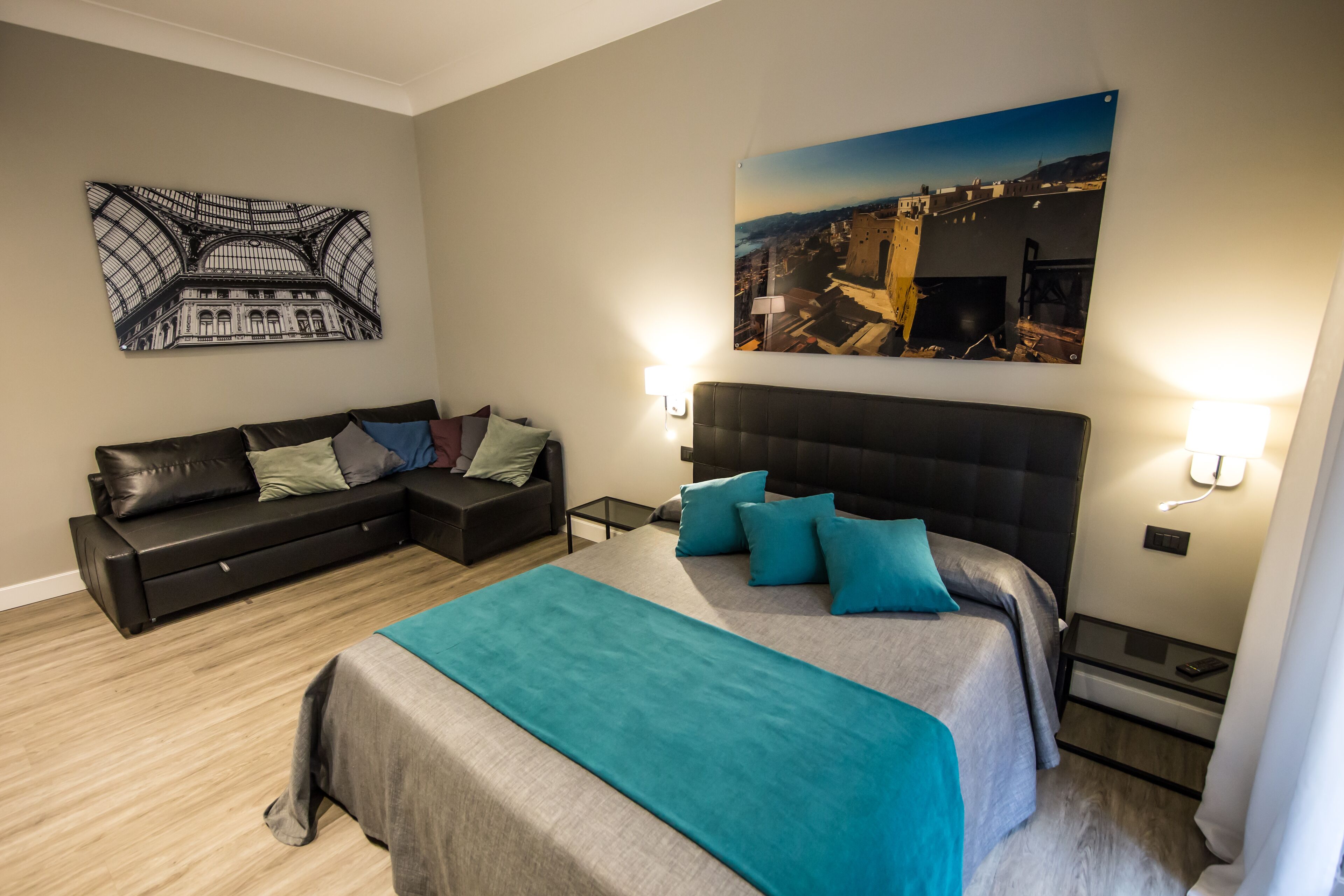 A modern bedroom with a large bed, a sofa, and two wall-mounted lamps.