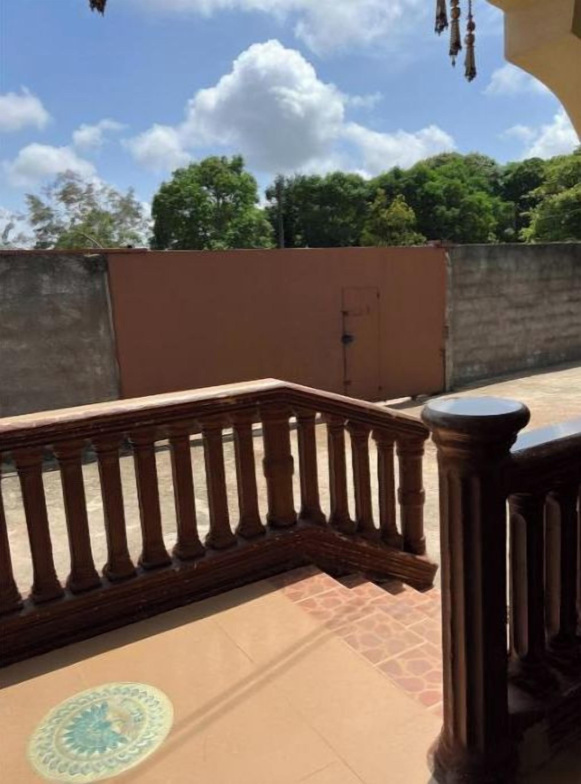 A rooftop terrace with a wooden balustrade, a concrete wall, and a clear sky.