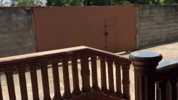 A rooftop terrace with a wooden balustrade, a concrete wall, and a clear sky.