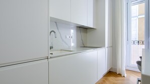 Een moderne keuken met witte kastjes, een marmeren spatwand en een houten visgraatvloer.