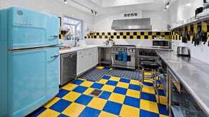 Eine moderne Küche mit einem blauen Kühlschrank, einem Schachbrettfußboden, Edelstahlgeräten und einem Oberlicht.