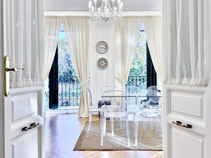 Ein Zimmer mit einem großen Fenster, einer Kandelaber und einem transparenten Glastisch mit Stühlen.