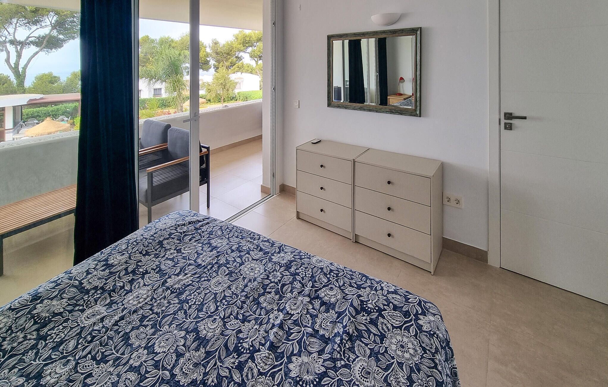 Un dormitorio con una cama, un aparador y una silla.