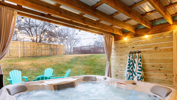 A hot tub with two chairs outside, wooden walls, and a wooden ceiling. - All Utilities! Hot Tub, Lg fenced yard, 10 min to DT, Office, Pets ~ Long Stays! (Asheville)