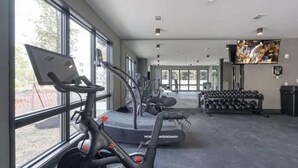 Une salle de sport équipée de matériel d’exercice, notamment un vélo d’appartement, un appareil elliptique et des haltères.