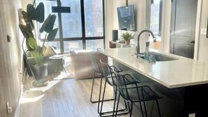 Une cuisine moderne dotée d’un îlot central, de tabourets de bar, d’une grande fenêtre et d’un ventilateur de plafond.