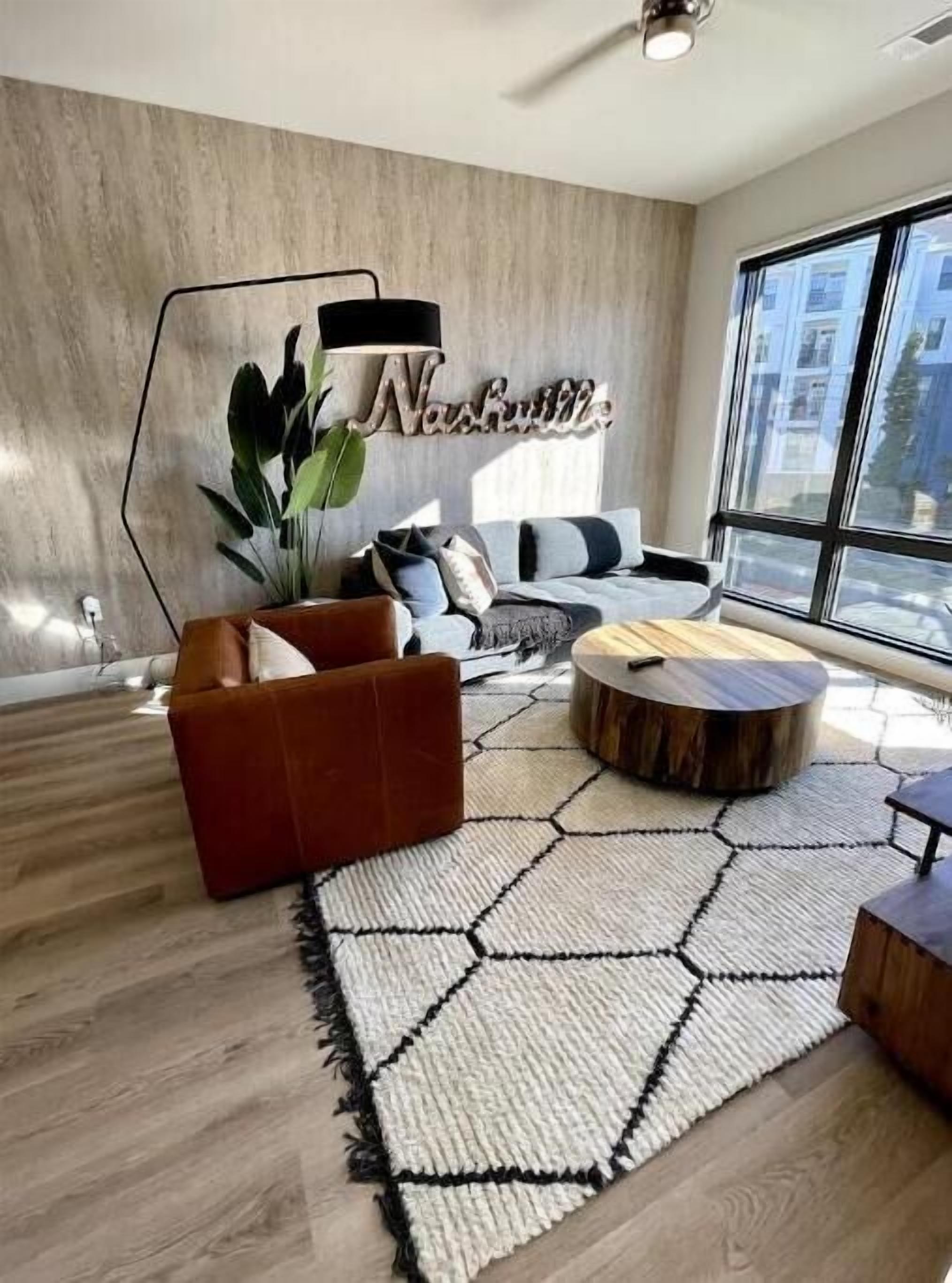 Una sala de estar moderna con un sofá, sillones, una mesa de centro y una planta grande.