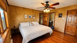 A bedroom with a bed, wooden floor, ceiling fan, and framed pictures on the wall. - Sundance & RMNP Escape Backing National Forest (Lyons)