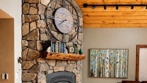 A stone fireplace with a clock, books, and decorative items. - Sundance & RMNP Escape Backing National Forest (Lyons)