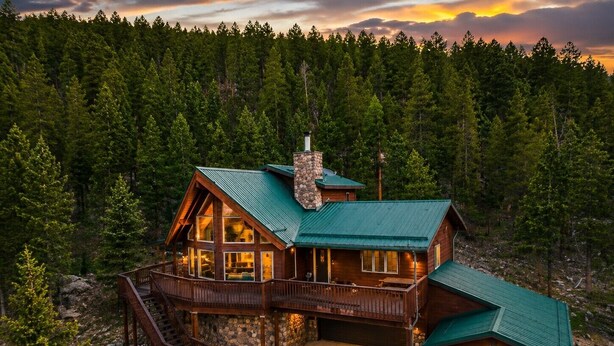A log cabin with a stone chimney, a deck, and a garage. - Sundance & RMNP Escape Backing National Forest (Lyons)