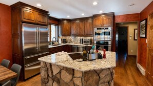 A kitchen with a stone island, stainless steel appliances, and wooden cabinets. - Sundance & RMNP Escape Backing National Forest (Lyons)