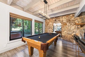 A pool table in a room with stone walls and large windows.
