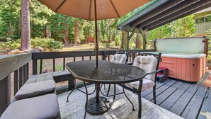 Una terraza con mesa y sillas, una sombrilla y un jacuzzi.